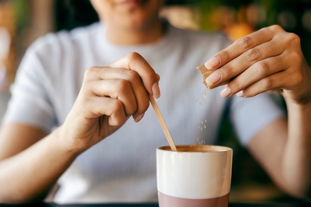 Une femme ajoute du sucre dans son café