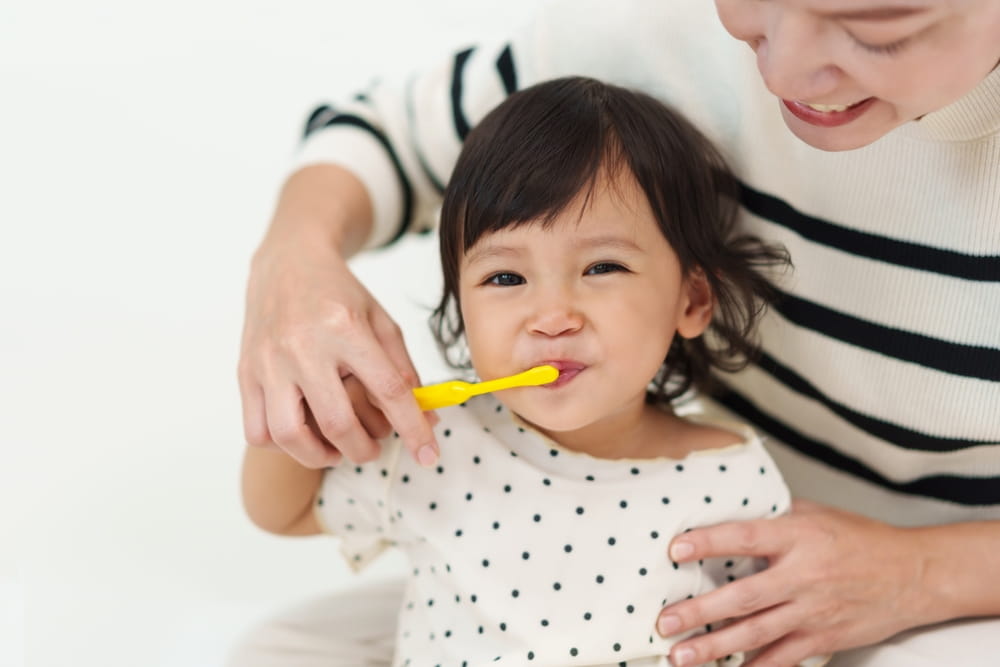 Brossage des dents pour une fillette avec l'aide de sa maman