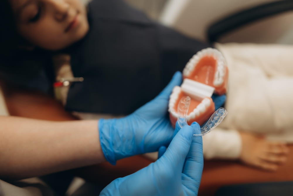 Une dentiste présente une gouttière transparente utilisée en orthodontie invisible à sa patiente